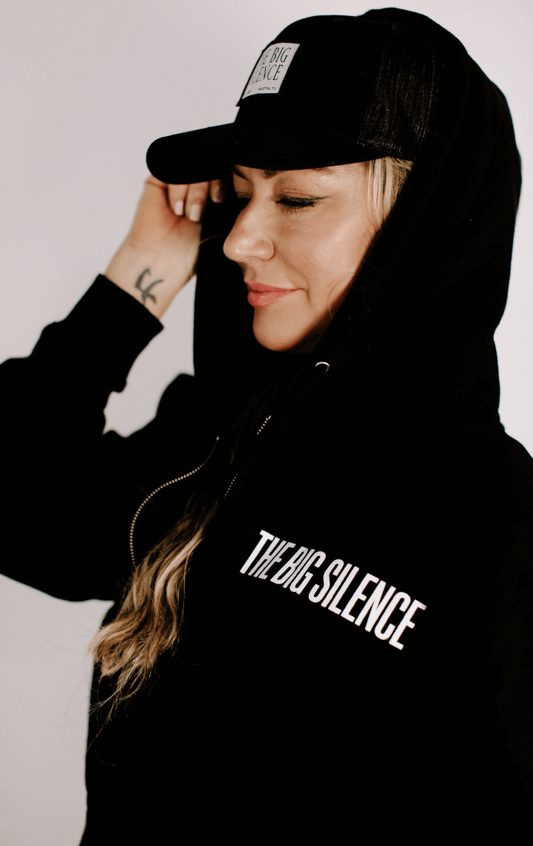 Karena in hoodie with hood up and trucker hat