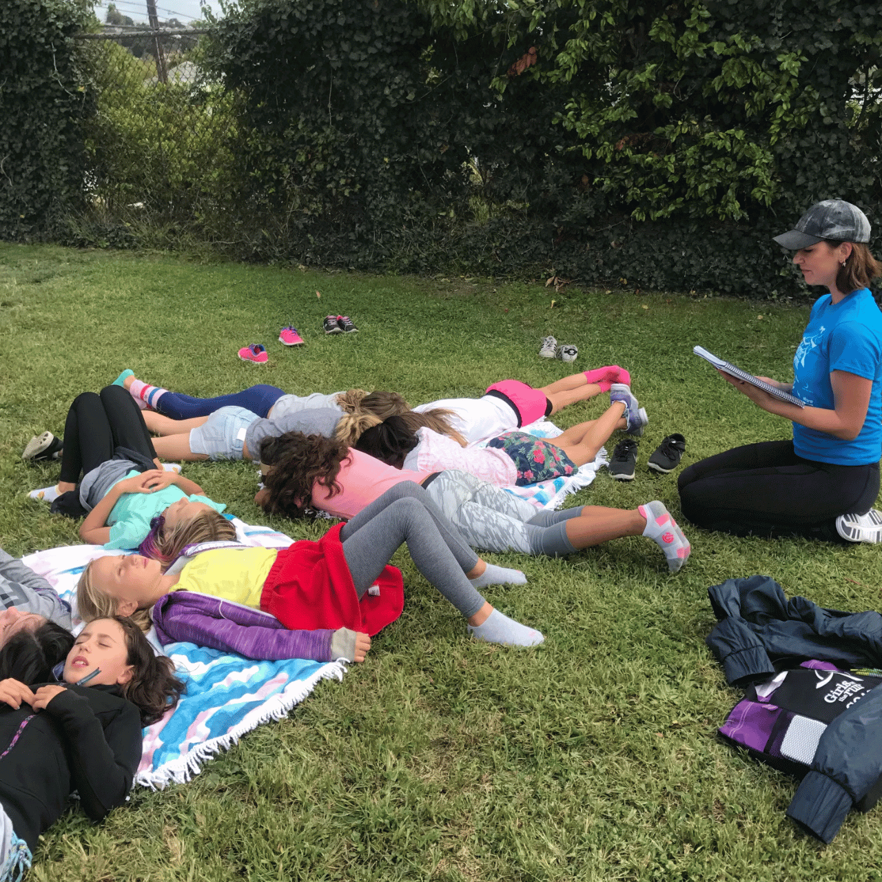 Karena Dawn on the grass with a group of girls teaching mindfulness and meditation for mental health